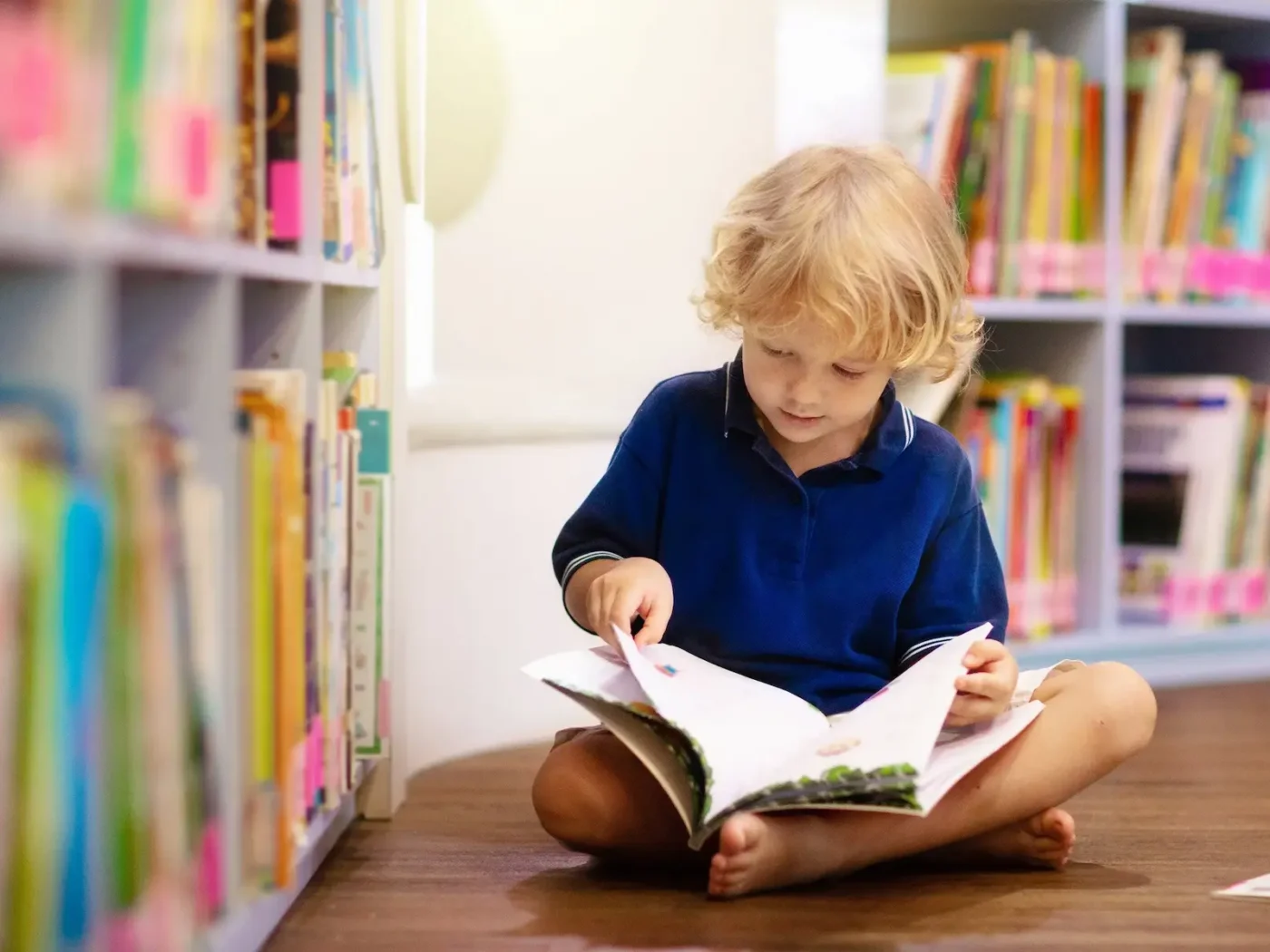 A young student reading beside a bookshelf