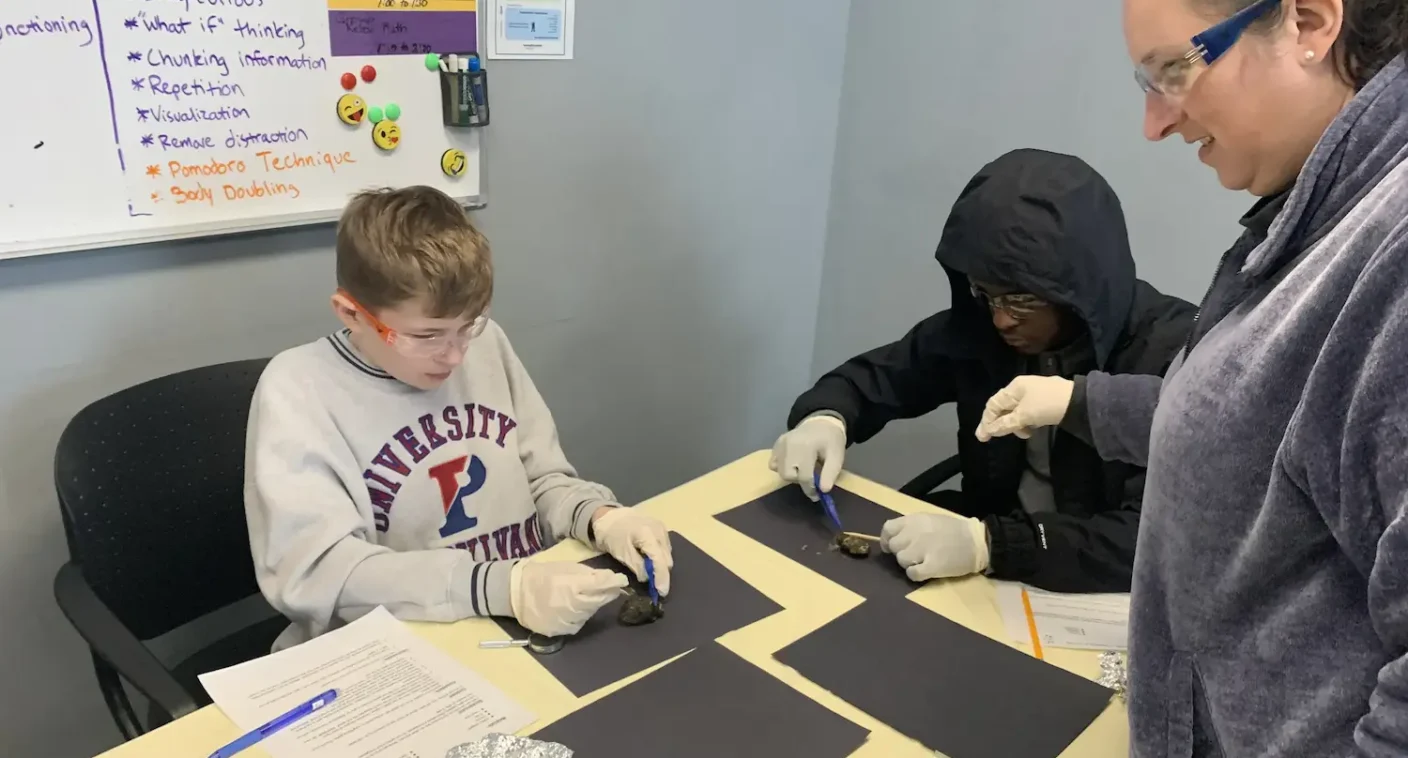 A teacher working with two students on a hands-on project at Balanced Learning Academy