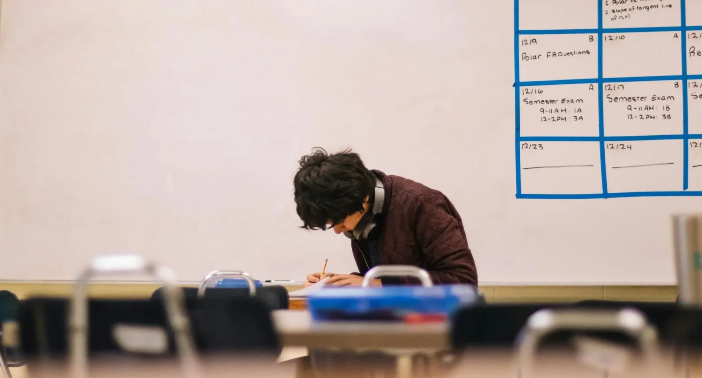 A high school student working at a desk in a classroom