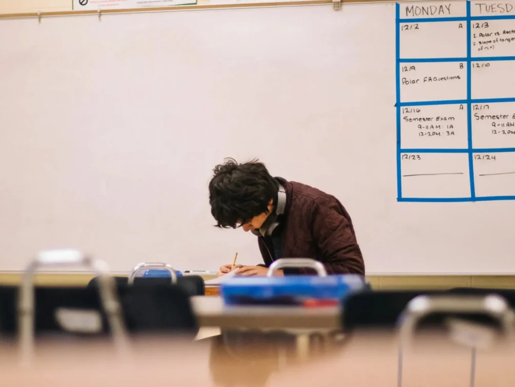 A high school student working at a desk in a classroom