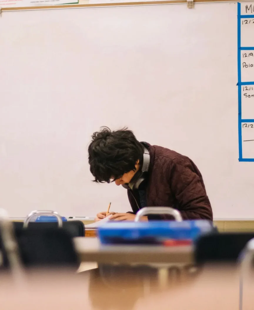 A high school student working at a desk in a classroom