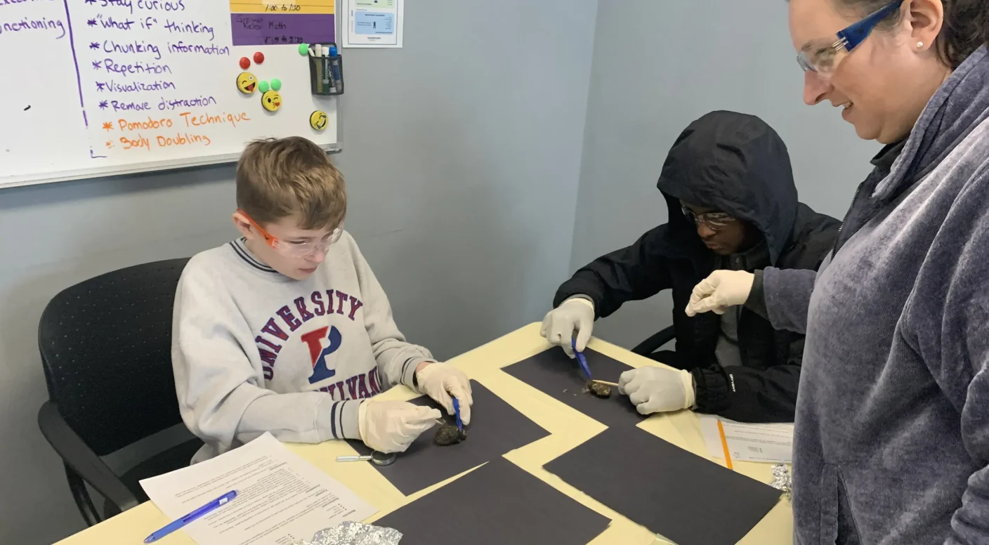 A teacher working with two students on a hands-on project at Balanced Learning Academy