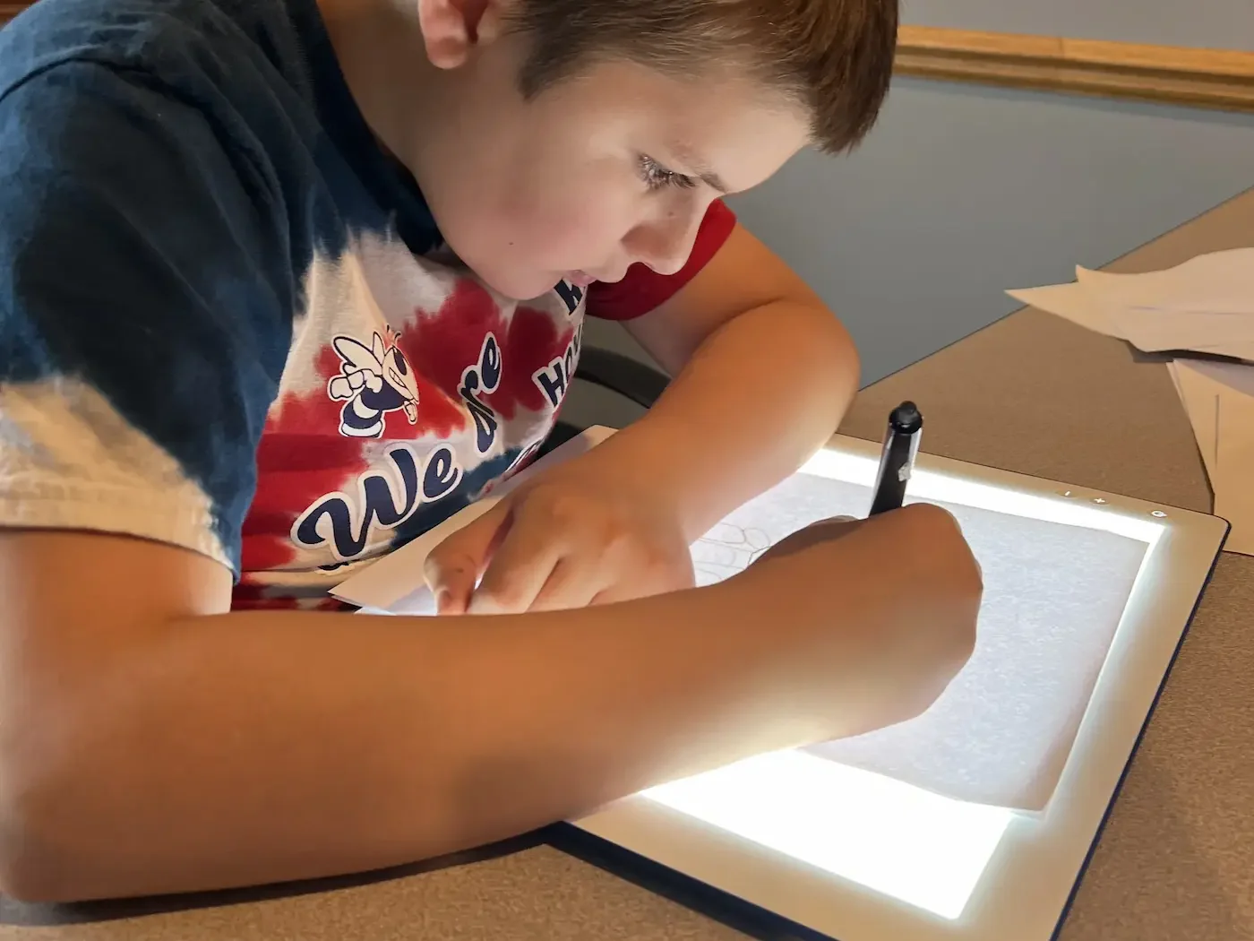 A student writing over a light box in class